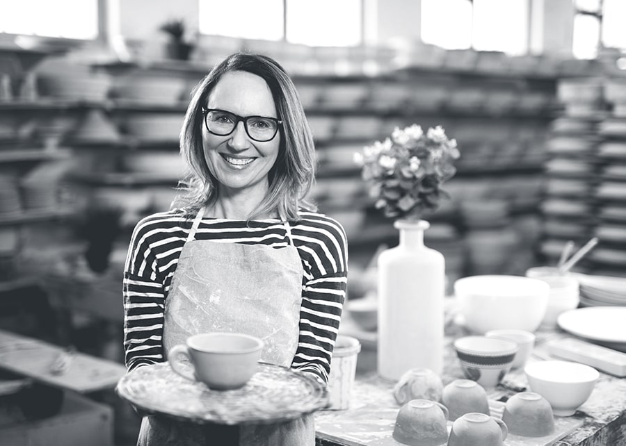 Woman in a pottery shop holding a tray with a piece of hand made pottery