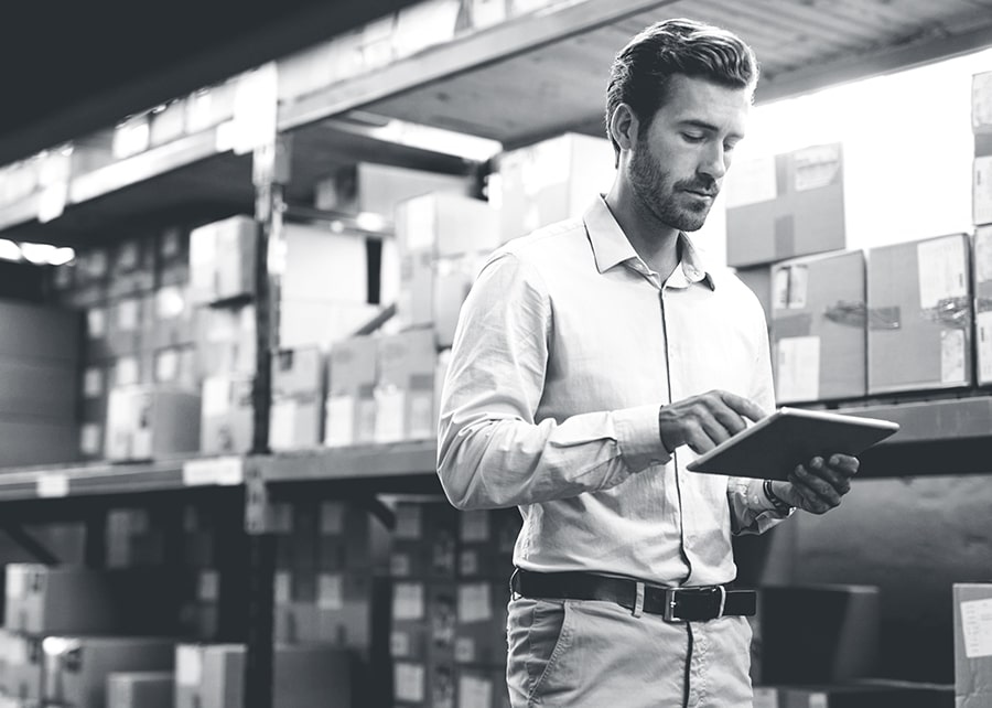 Man in warehouse glancing at an ipad