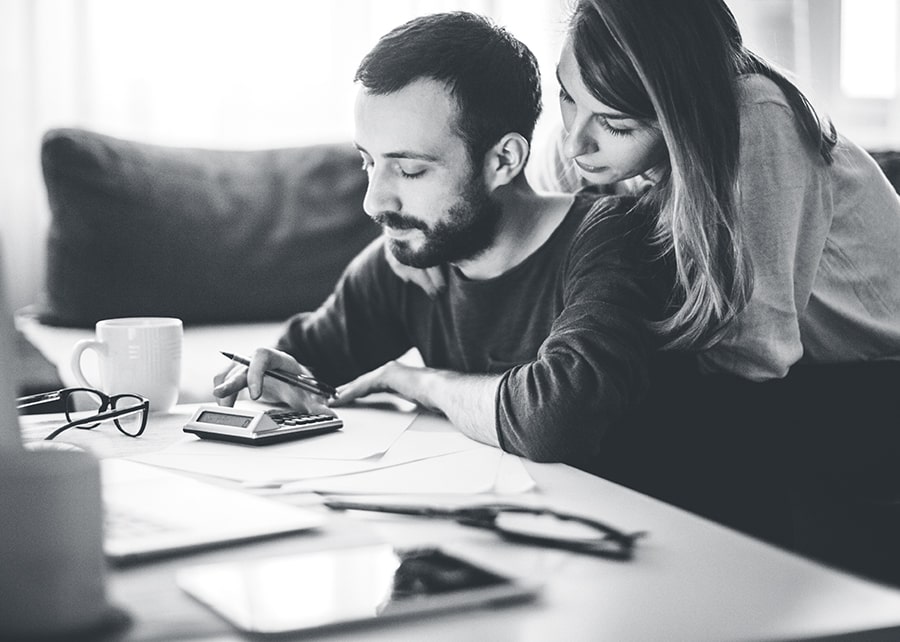 Man and woman looking down at calculator on desk