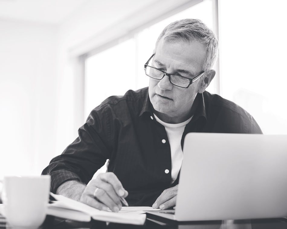 Man sitting looking at laptop and paperwork
