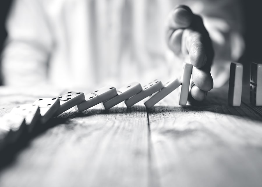 Hand stopping a row of dominoes from continuing to fall