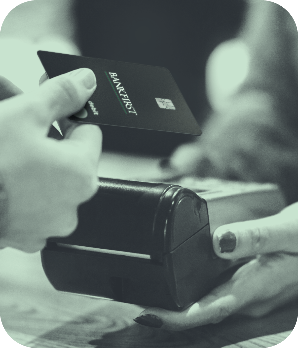 Hand holding out BankFirst Debit Card to another hand holding card processor