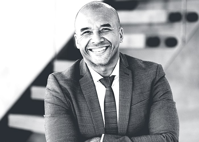 Smiling man with arms folded in front of stairs