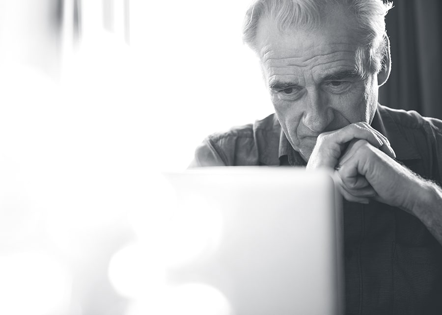 Man glancing at computer screen with hands cupped in front of his face