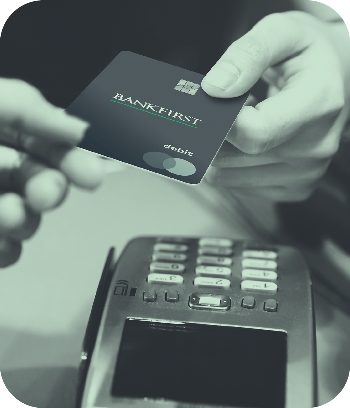 Hand holding over BankFirst Debit Card with a card processor nearby