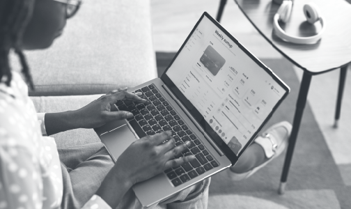 Woman sitting on couch with laptop in lap and hands on keyboard