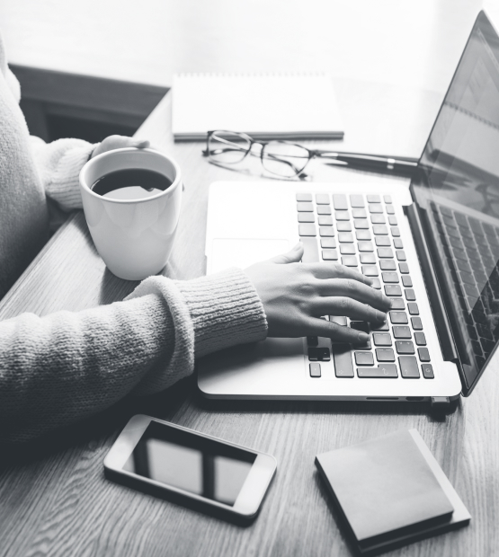 Woman working at desk with coffee, phone and laptop
