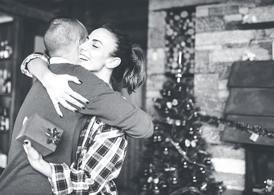 Man and woman hugging in front of a Christmas tree
