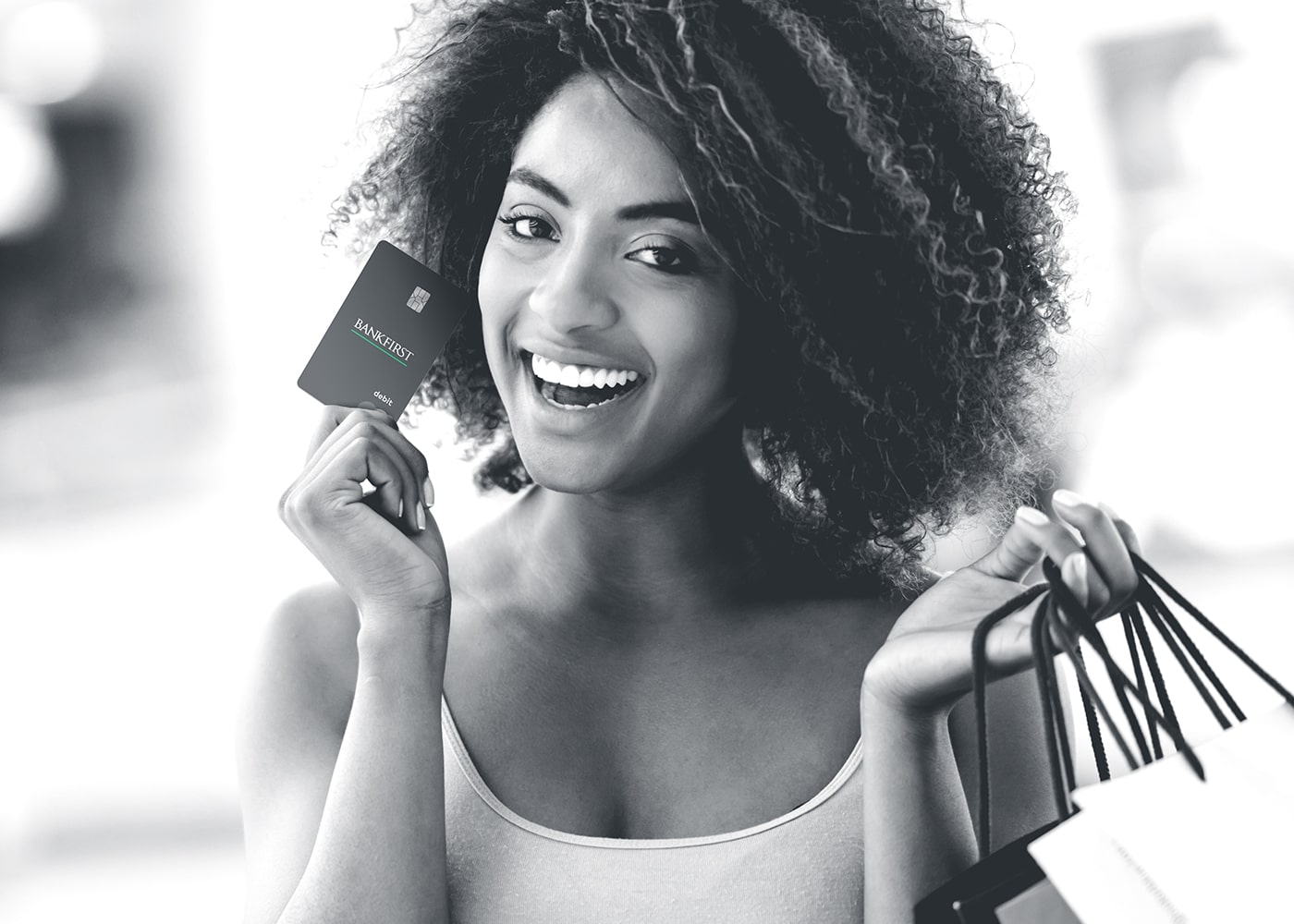 African American female smiling while holding the BankFirst consumer debit card