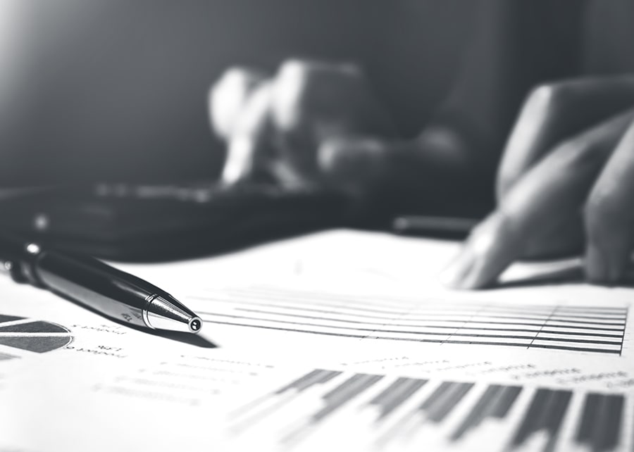 Hands scanning budget printout with pen and calculator nearby