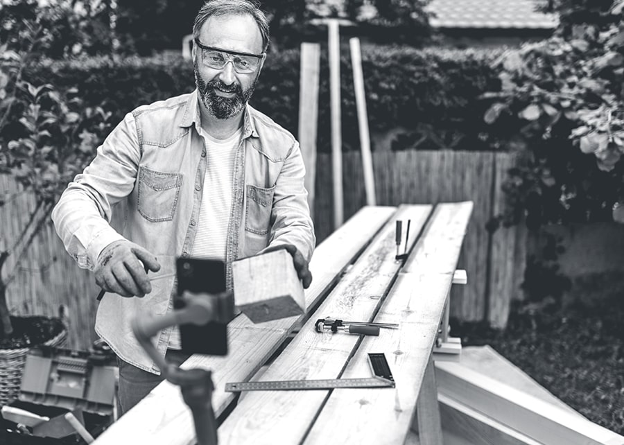 Man wearing safety goggles holding a piece of lumber on a project
