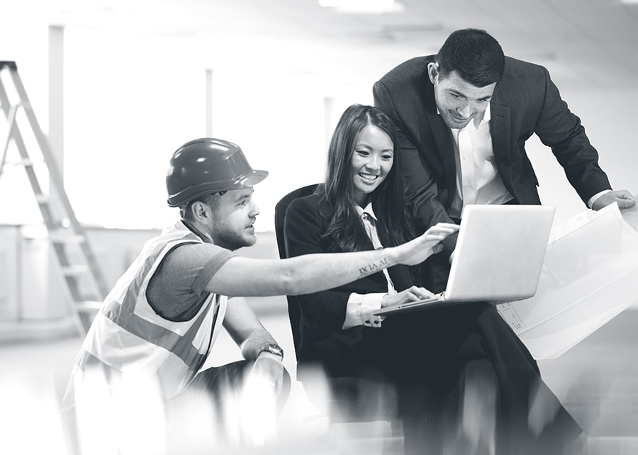 Business man and woman meeting with a construction man while viewing a laptop and paper plans