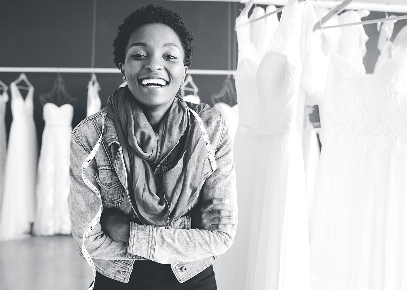 African American female smiling with her arms crossed in front wedding dresses